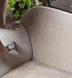 Professional upholstery cleaner deep-cleaning a fabric sofa with a handheld extraction tool and hose Fort Worth, TX.